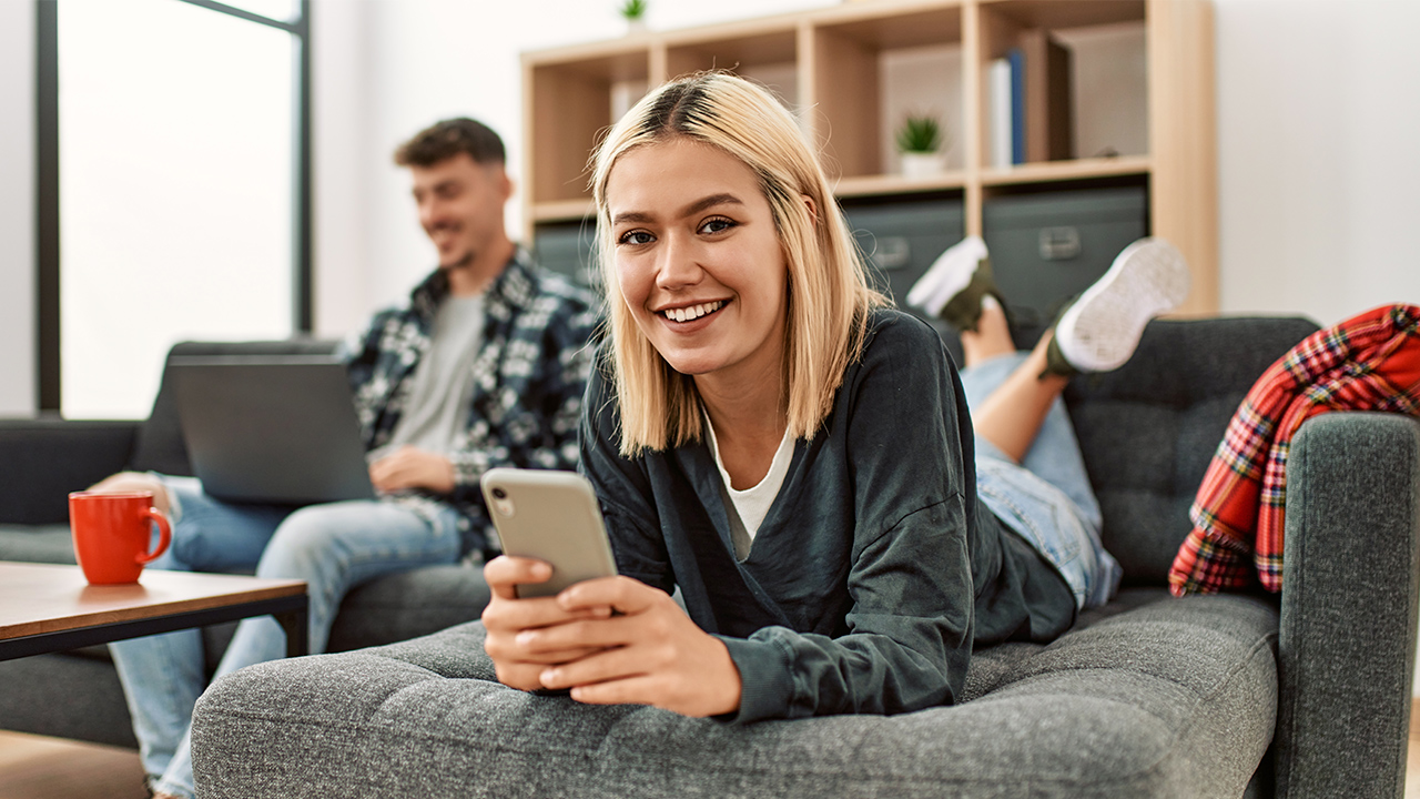jóvenes compartiendo piso con móvil y tableta en la mano
